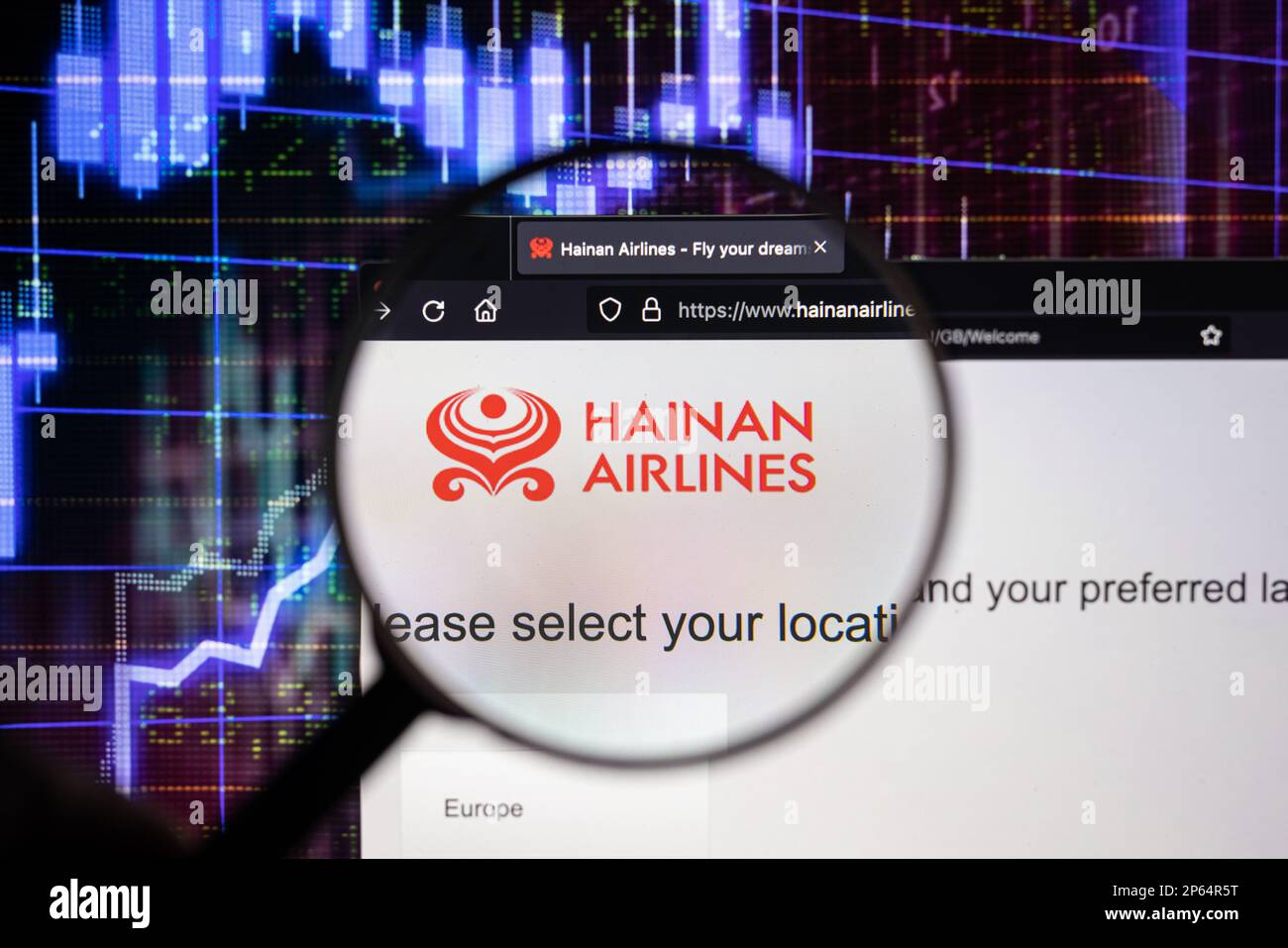 Firmenlogo von Hainan Airlines auf einer Website mit verschwommenen Aktienmarktentwicklungen im Hintergrund, auf einem Bildschirm durch eine Lupe zu sehen Stockfoto