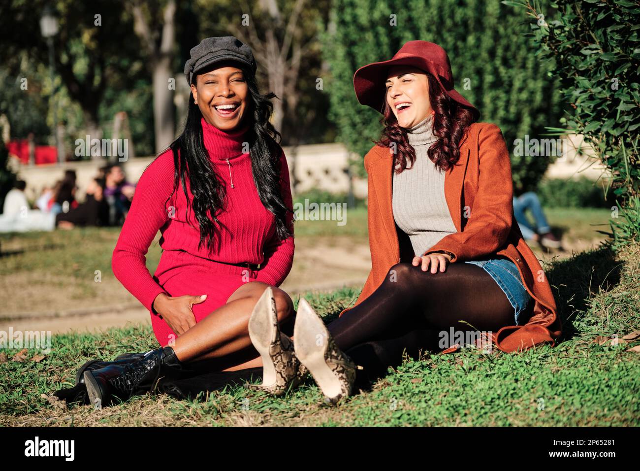 Stilvolle, multiethnische Freunde sitzen in einem Park unter der Sonne Stockfoto