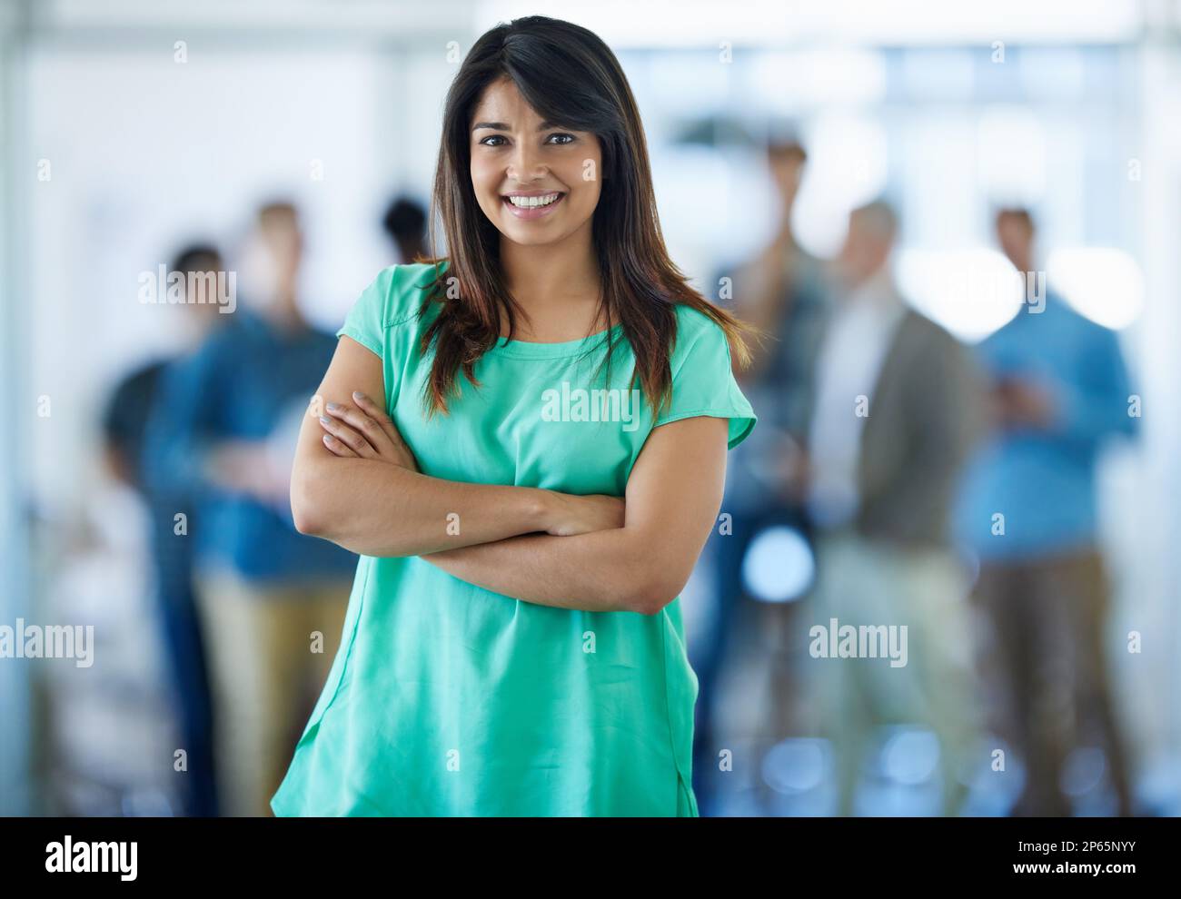 Ich verdanke meinen Erfolg Teamwork. Porträt einer jungen Büroangestellten mit ihren Kollegen im Hintergrund. Stockfoto