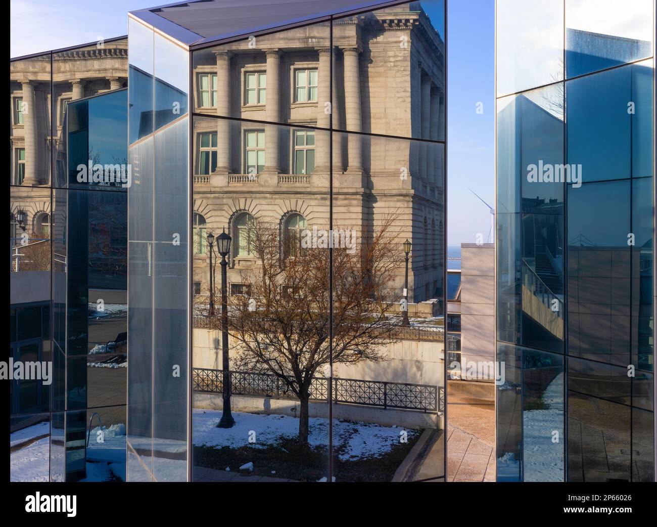 Ein Glasbau in einem öffentlichen Park spiegelt die Strukturen und Szenen in einem öffentlichen Stadtpark in der Innenstadt von Cleveland, Ohio, USA wider. Stockfoto