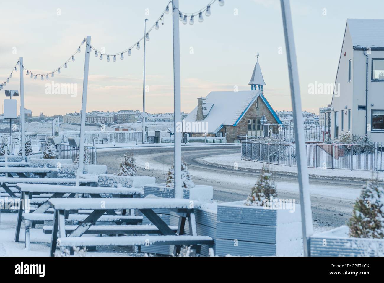 Das Cullercoats Watch House ist mit Schnee bedeckt, der durch die Lichter des Queens Head Pubs an der Front Street fotografiert wurde Stockfoto