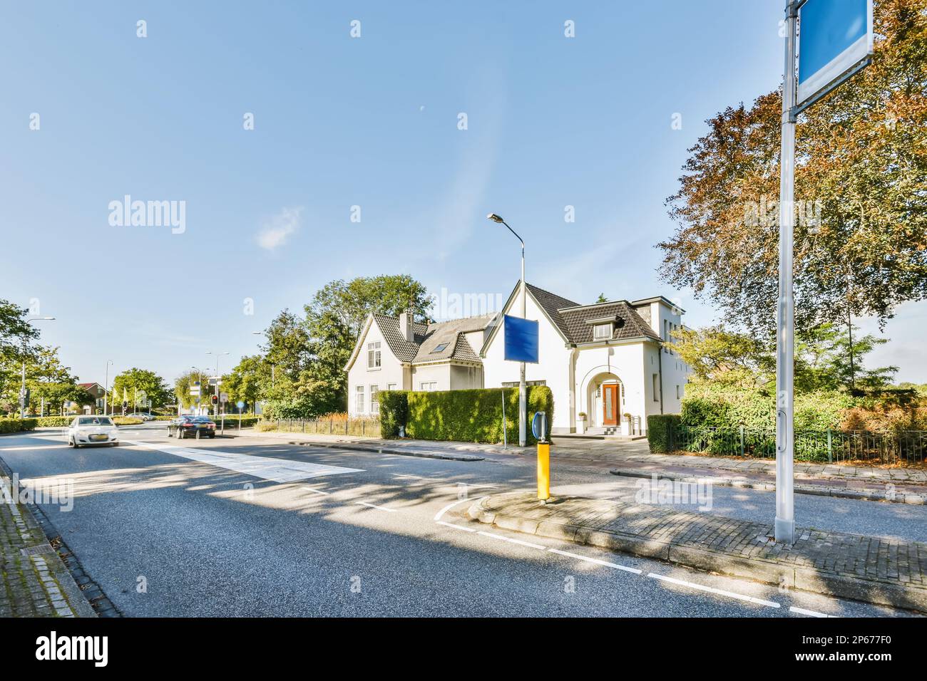 Amsterdam, Niederlande - 10. April 2021: Eine Straße mit Häusern und Bäumen in der Mitte des Fotos wird von der anderen Straßenseite rechts aufgenommen Stockfoto