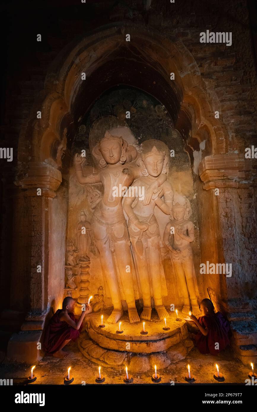 Zwei Anfängermönche mit Kerzen an der Statue im Inneren des Tempels, Bagan (Pagan), UNESCO-Weltkulturerbe, Myanmar (Birma), Asien Stockfoto