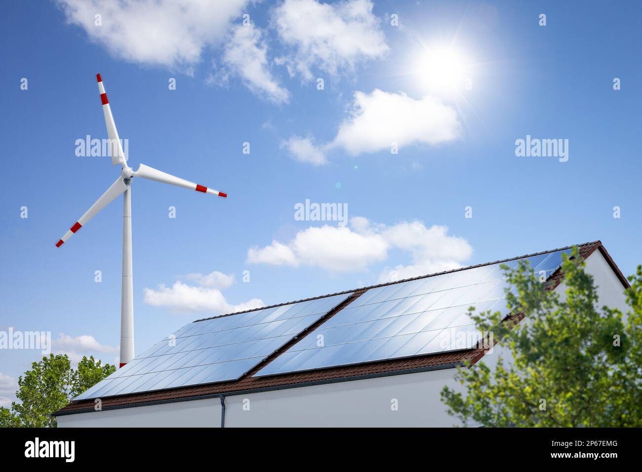 Solarpaneele auf einem Dach und eine Windturbine zur Erzeugung erneuerbarer Energie Stockfoto