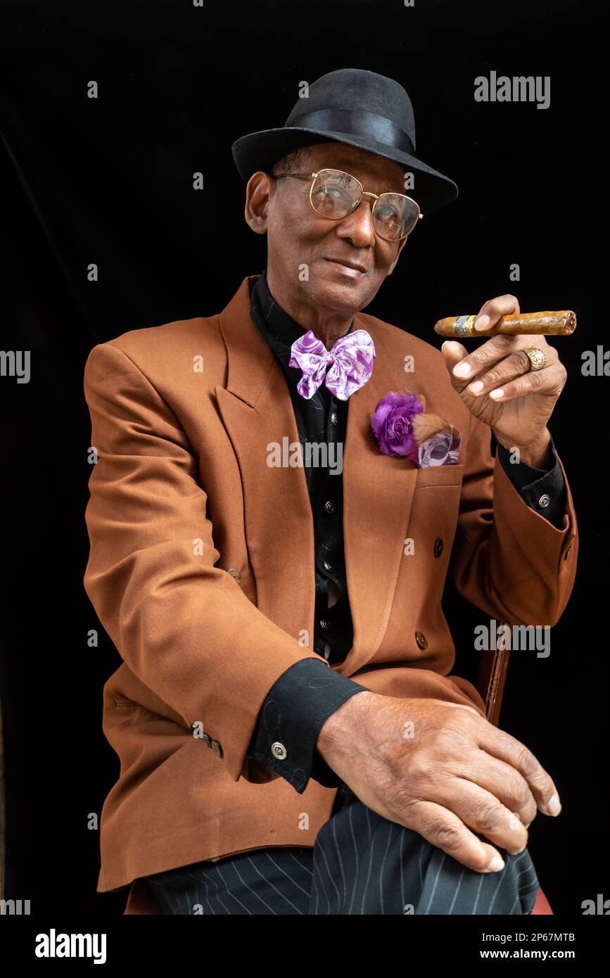 Mann sitzt als 1950er Dandy oder Gangster mit Fedora-Hut und großer Zigarre, Havanna, Kuba, West Indies, Karibik, Mittelamerika Stockfoto