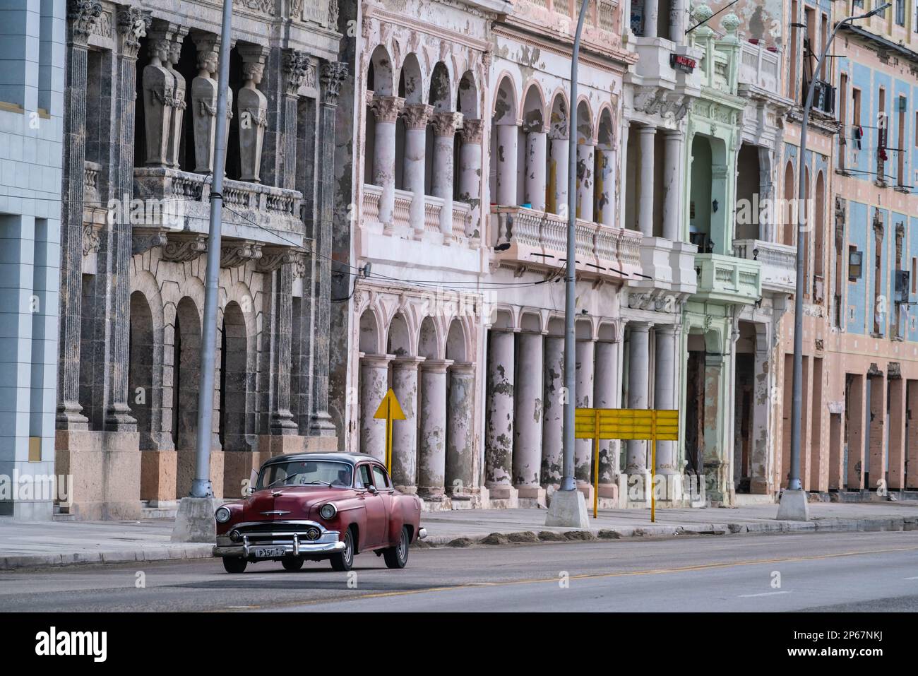 Verblasste Pracht, Stuck, wetterbefallene Häuser am Meer von Malecon, mit rotem Oldtimer, Havanna, Kuba, Westindien, Karibik, Mittelamerika Stockfoto