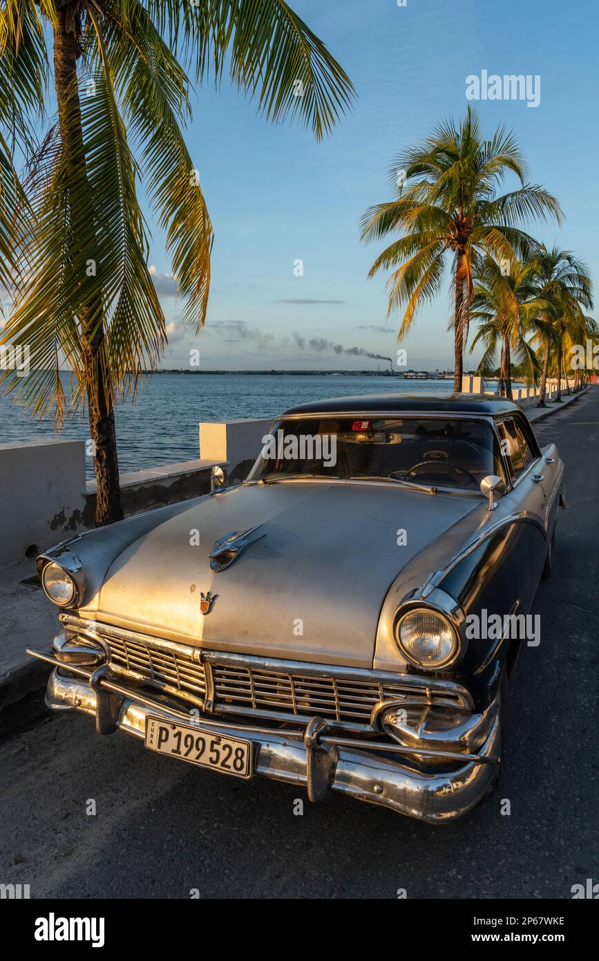 Klassisches silbernes Ford Auto parkt auf einsamer Küstenstraße, Raffinerie im Hintergrund, Cienfuegos, Kuba, West Indies, Karibik, Mittelamerika Stockfoto