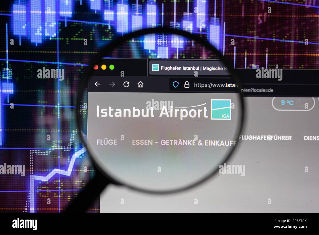 Firmenlogo am Flughafen Istanbul auf einer Website mit verschwommenen Entwicklungen am Aktienmarkt im Hintergrund, auf einem Bildschirm durch eine Lupe zu sehen Stockfoto