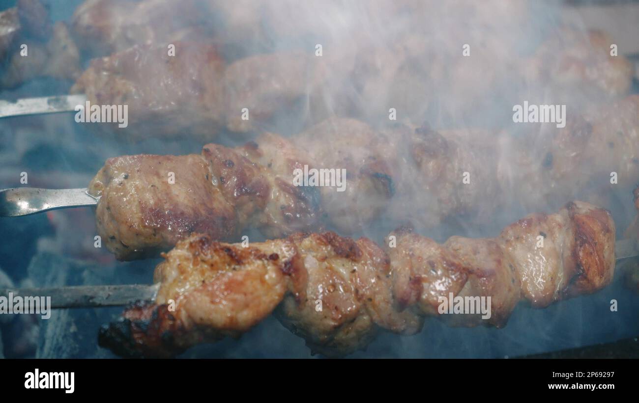 Nahaufnahme Pommes Frites Fleischspieße. Barbecue auf Spießen. Barbecue-Grill. Freizeit, Essen, Leute, Urlaub. Konzept - ein Mann kocht Fleisch auf einem Grill für Stockfoto