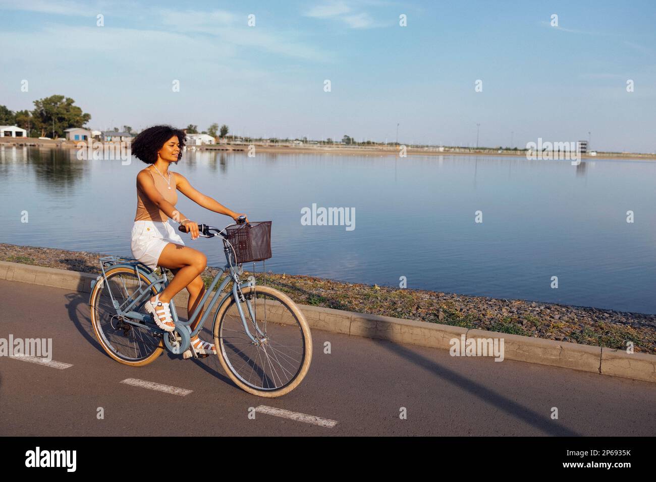 Eine dunkelhäutige Teenagerin fährt ihr Fahrrad. Ein junges und positives afro-amerikanisches Mädchen in lässiger Kleidung lächelt süß und hat Spaß. Stadtstraße an Stockfoto