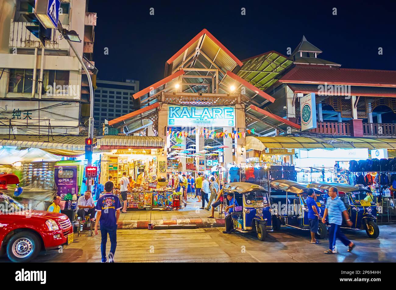 CHIANG MAI, THAILAND - 3. MAI 2019: Beleuchteter Pavillon des Nachtmarkts Kalare mit kleinen Verkaufsständen und geparkten Tuk-Tuk-Taxis im Vordergrund, o Stockfoto
