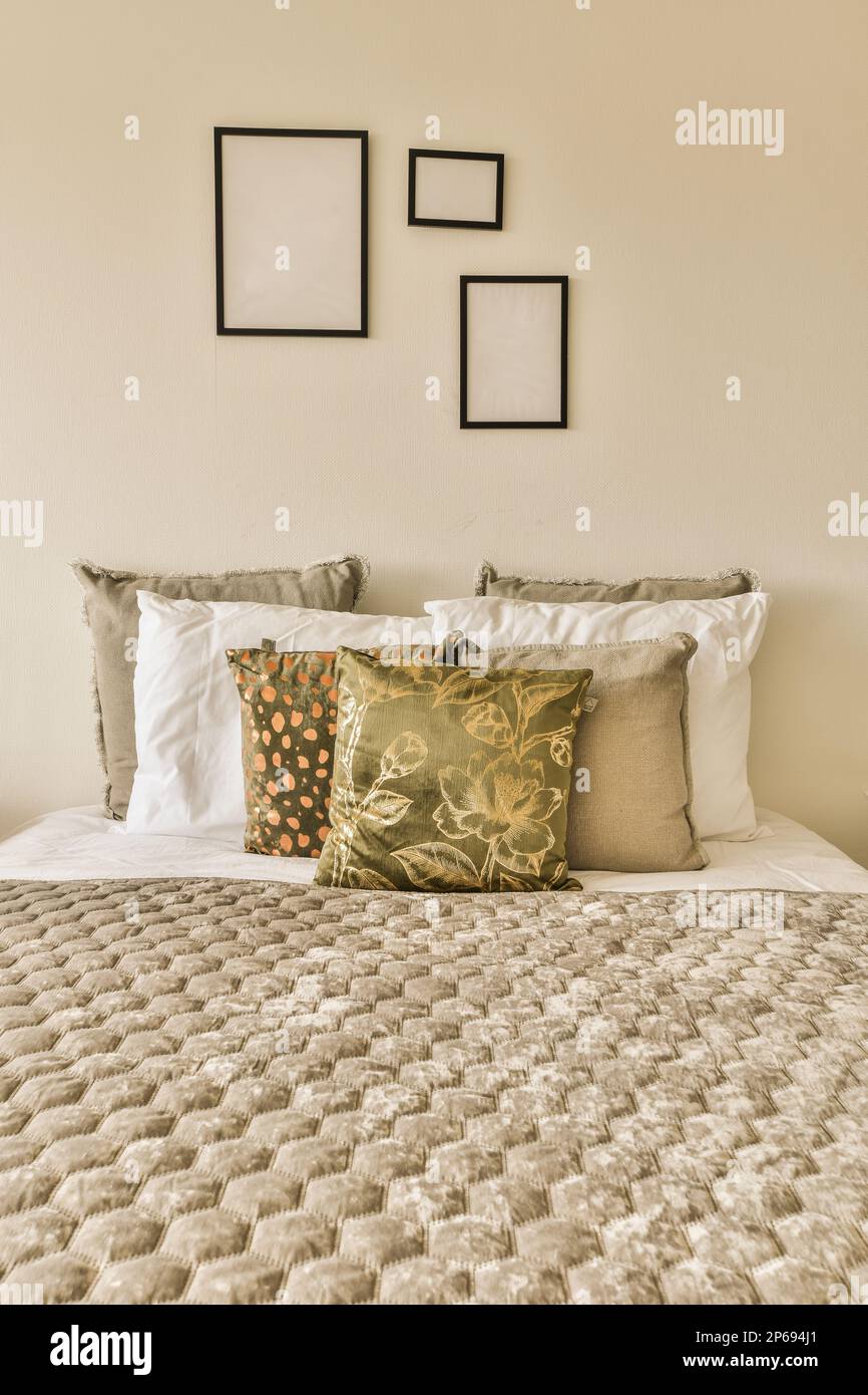 Ein Bett mit Kissen und Bildern, die an der Wand darüber hängen, in einem  Schlafzimmer, das sauber ist und für die Gäste bereit ist Stockfotografie -  Alamy