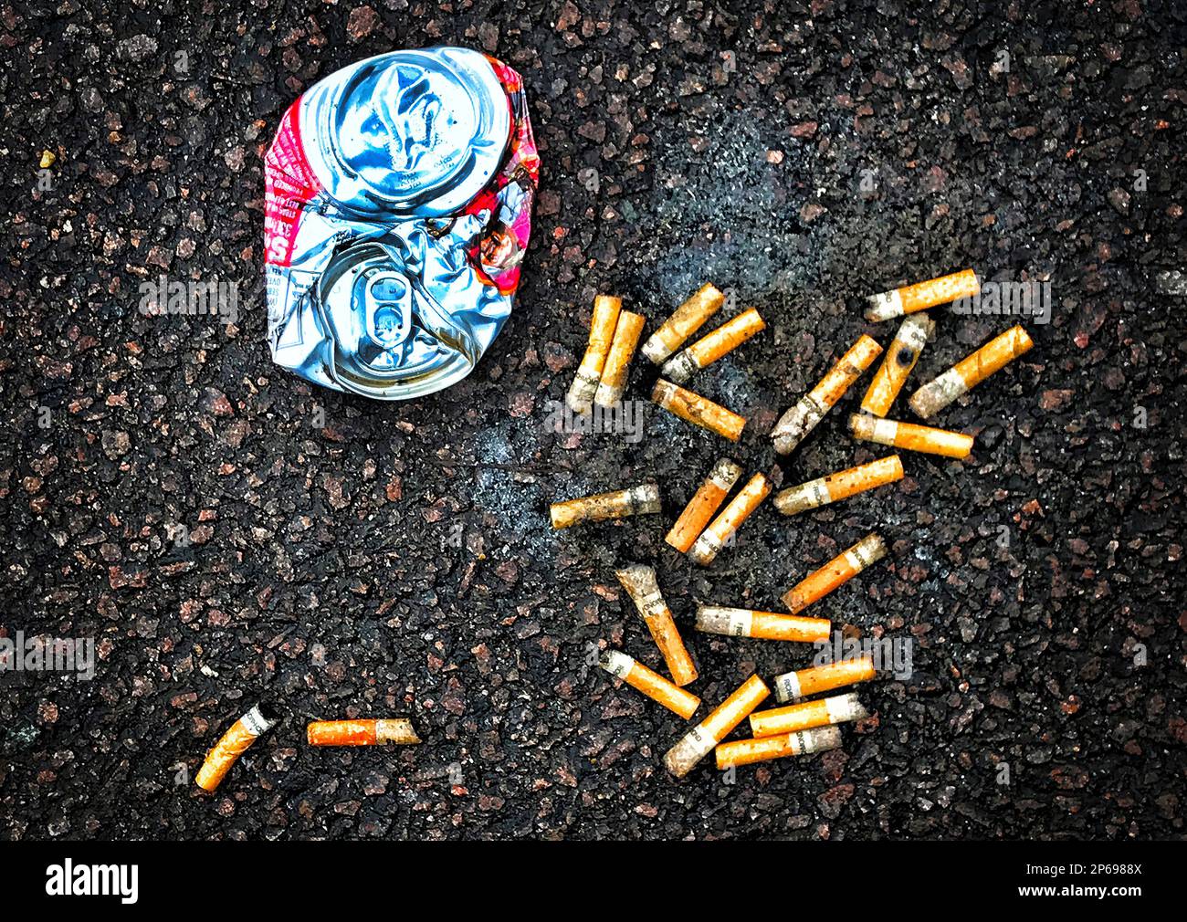 Weggeworfene Müll-Zigarettenkippen und eine Getränkedose Stockfoto