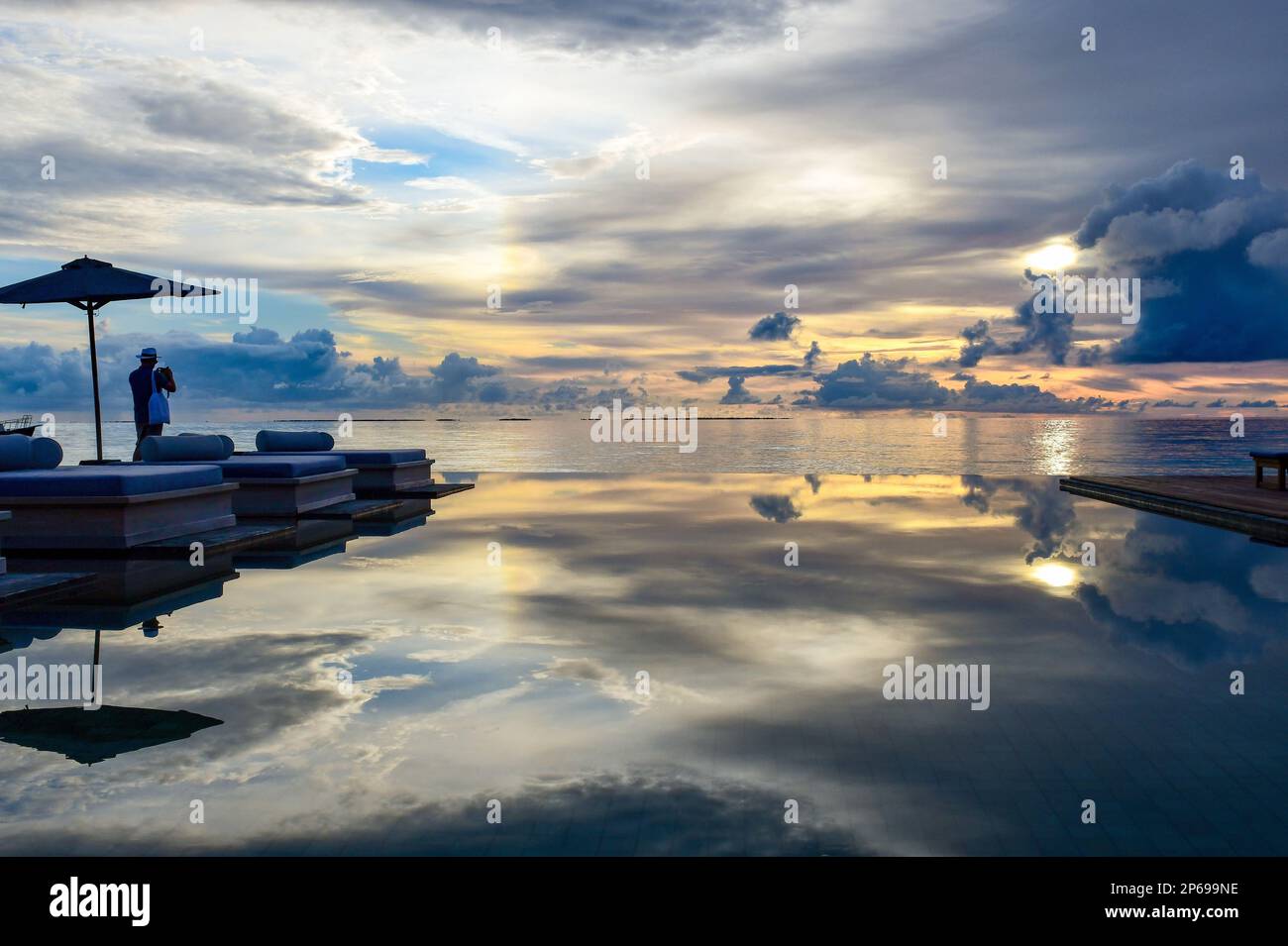 Ein Tourist am Infinity-Pool eines Luxusresorts, der Fotos vom Sonnenuntergang, den Malediven, macht Stockfoto