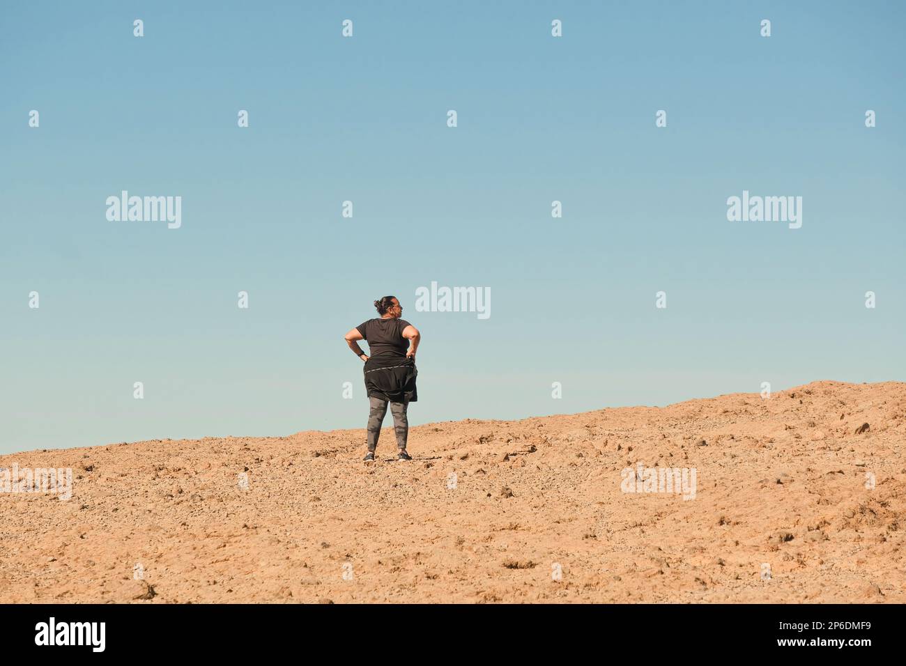 Verlorene und müde Seniorin in einer felsigen Landschaft nach dem Wandern. Sonniger und klarer Himmel Stockfoto