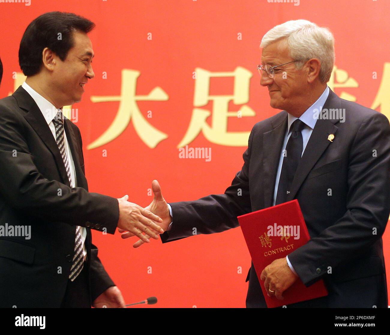 Xu Jiayin (L), chairman of Chinese Super League team Guangzhou Evergrande, shakes hands with Italian coach Marcello Lippi (R) during a news conference in Guangzhou in south China's Guangdong province on Thursday, May 17, 2012. World Cup-winning Italian coach Marcello Lippi has been hired to coach Chinese Super League team Guangzhou Evergrande and plans to bring an Italian style to the club.(Photo By Fang Yingzhong/Color China Photo/AP Images) Stockfoto