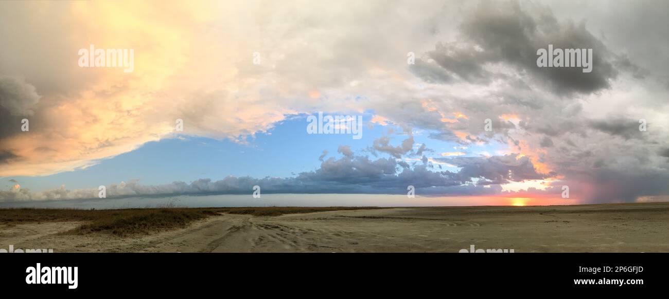 Afrikanischer Sonnenuntergang über der Salzpfanne. Flache Landschaft mit Panoramablick auf Sonne, Wolken, blauer Himmel. Makgadikgadi Salzwannen, Botsuana, Afrika Stockfoto