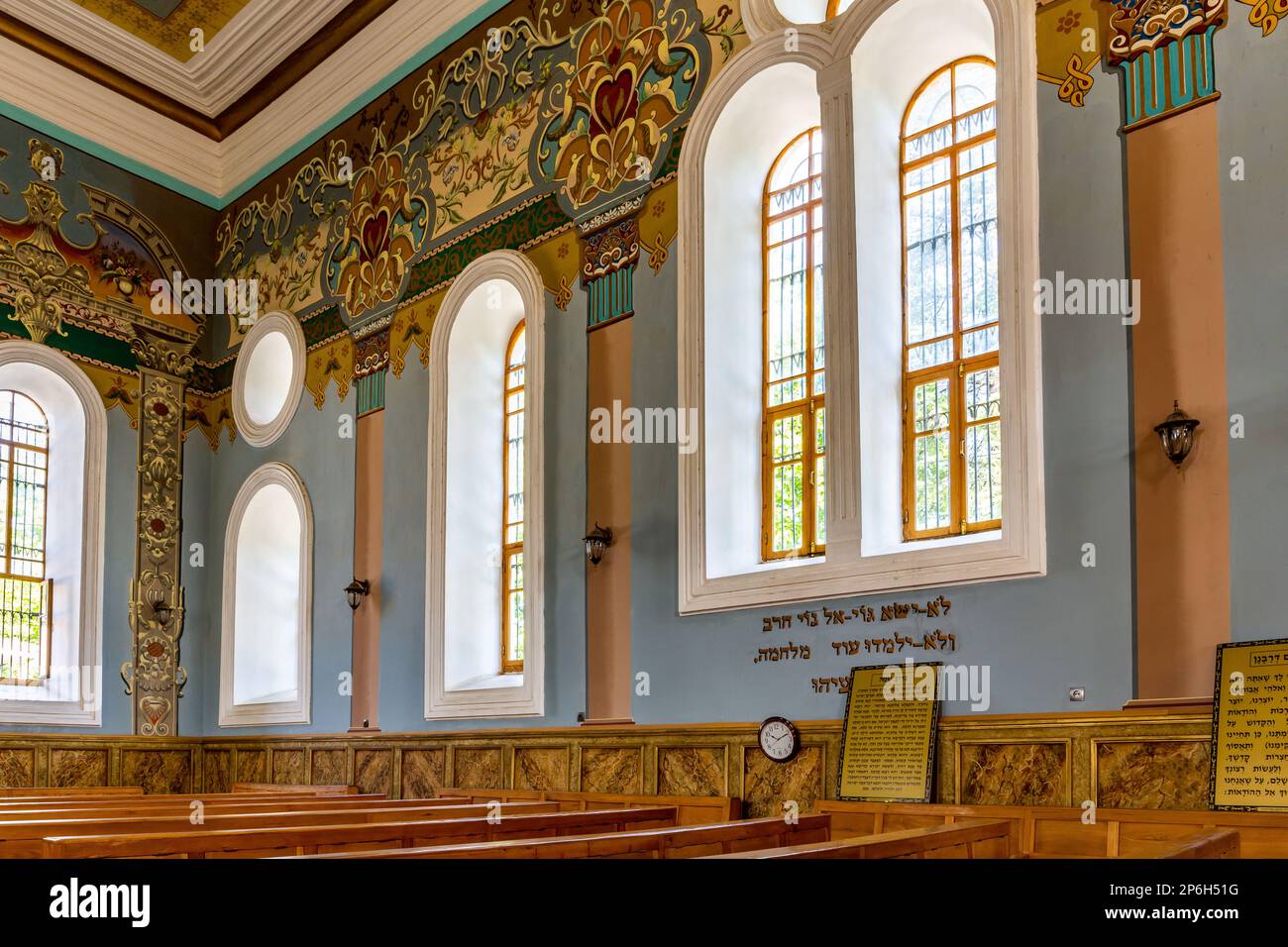 Kutaisi, Georgia, 04.06.21. Kutaisi-Synagoge von innen mit Blick auf die reich verzierte Seitenwand und Holzbänke sowie farbenfrohe Gemälde an der Synagoge. Stockfoto