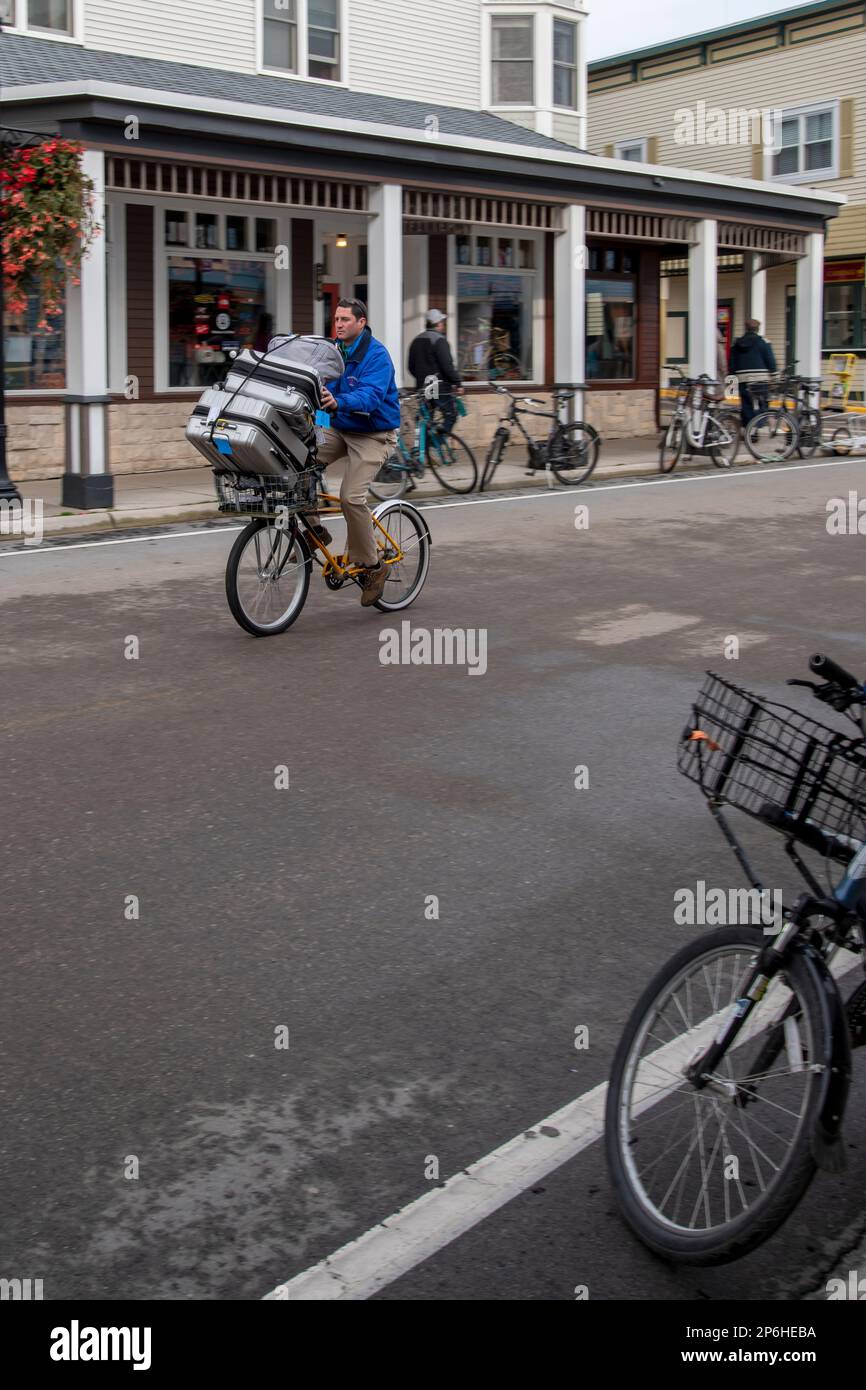 Mackinac Island, Michigan. Auf der Insel sind nur Pferde und Fahrräder erlaubt. Mann auf dem Fahrrad, der Gepäck für das Hotel vor Ort liefert. Stockfoto