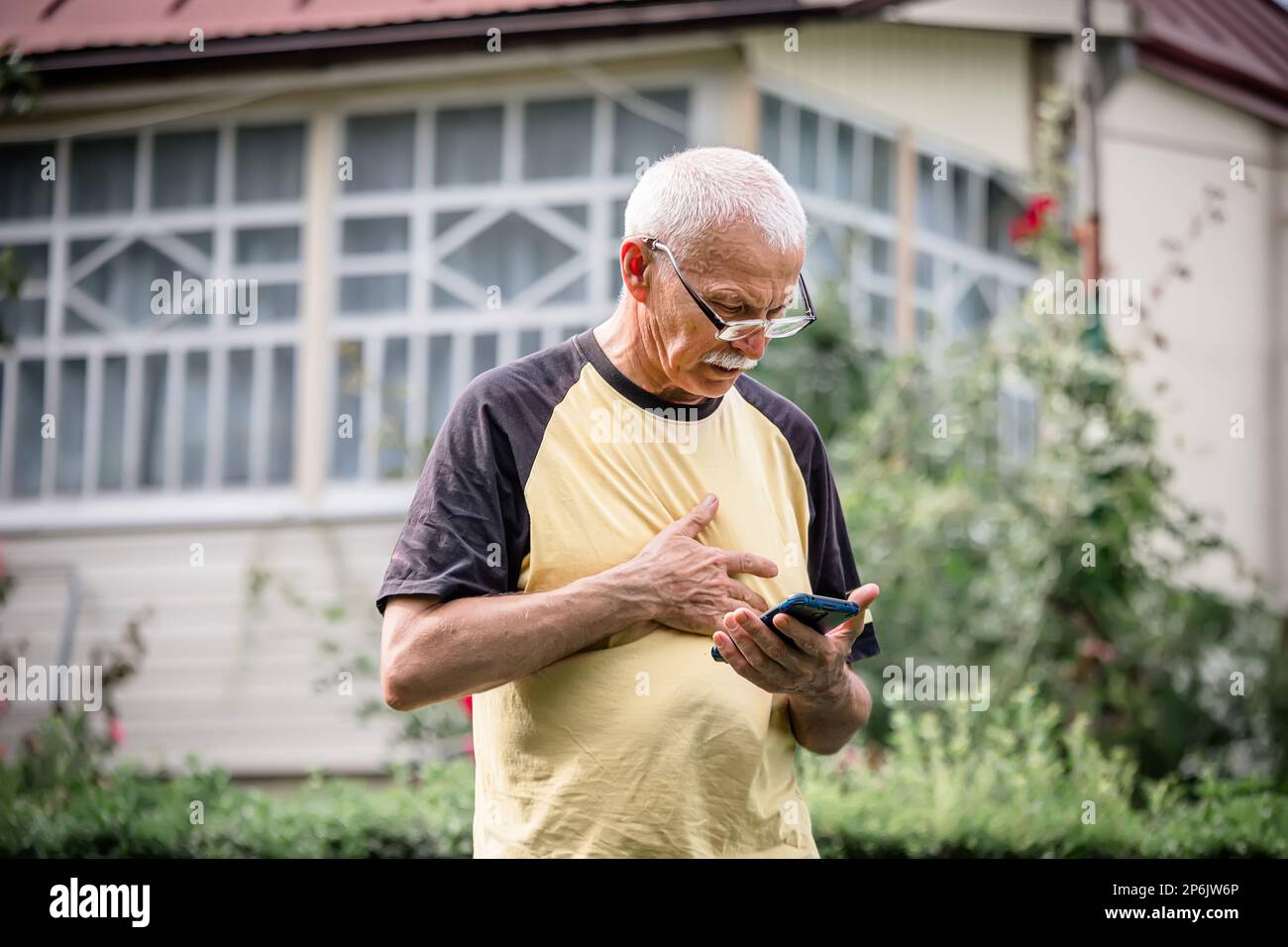 Ein älterer Mann entspannt einen angespannten Nerv im Brustbereich durch Drücken. Telefonische Behandlung aus der Ferne. Online-Therapeut. Teletherapie. Stockfoto