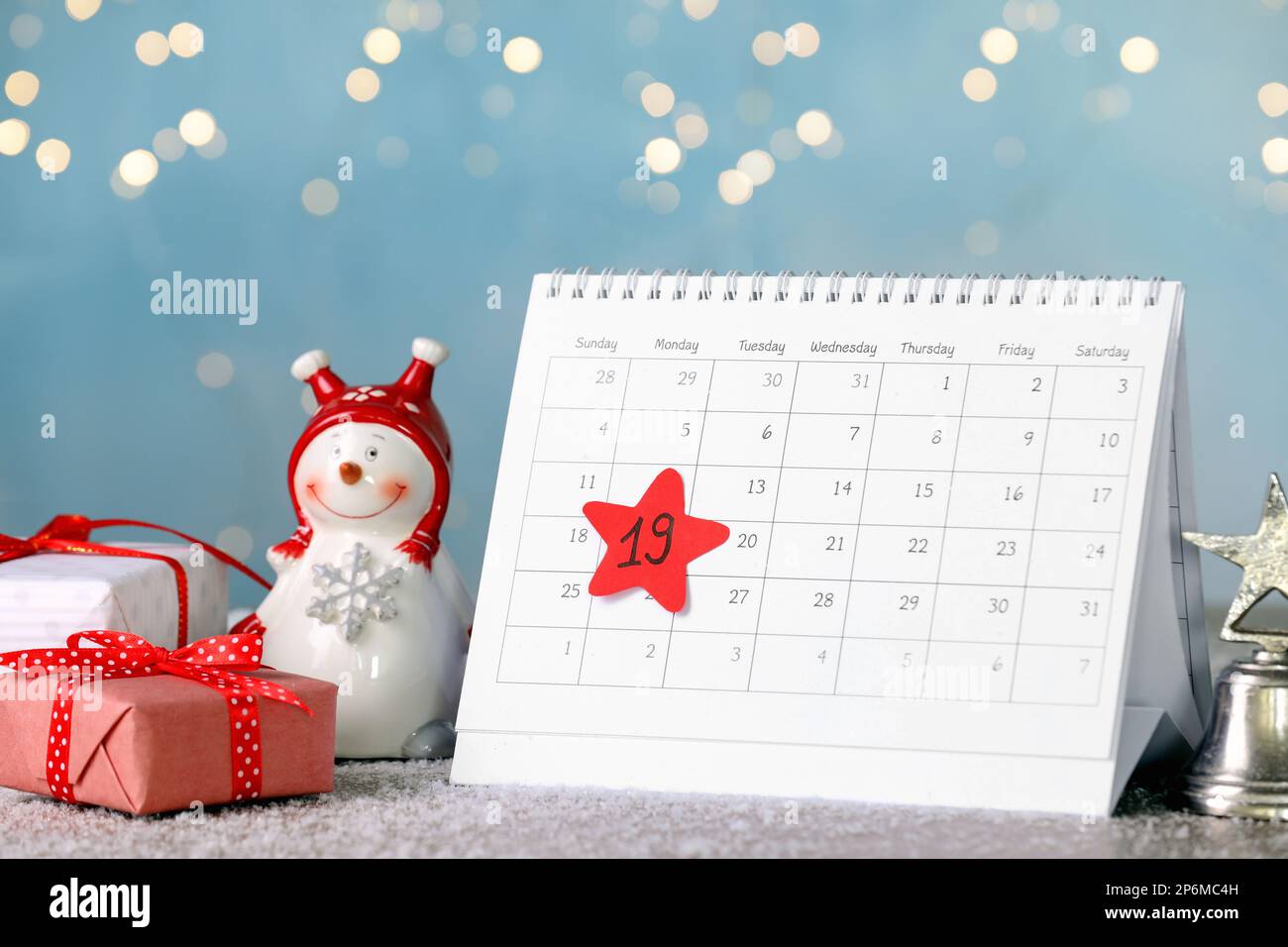 Nikolaustag. Kalender mit dem Datum Dezember 19, Geschenkboxen und Schneemannfigur auf dem Tisch vor verschwommenen Lichtern Stockfoto