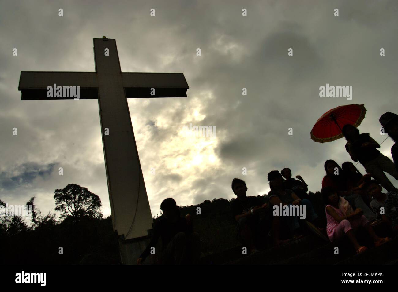 Silhouette von Besuchern und ein hohes christliches Kreuz im Bukit Kasih (Hügel der Liebe), einem beliebten religiösen Reiseziel im Dorf Kanonang, West Kawangkoan, Minahasa, North Sulawesi, Indonesien. Gewidmet allen religiösen Gläubigen und Gläubigen, während sie die Geister der Liebe, des Friedens und der Toleranz fördern; Bukit Kasih wurde Anfang 2000 gegründet, als Adolf J. Sondakh Gouverneur der Provinz Nord-Sulawesi war. Sie wurde als noble Friedensinitiative betrachtet; eine Reaktion auf Konflikte auf Grund der Religion und der ethnischen Zugehörigkeit geschah vor und um 2000 in mehreren anderen Provinzen. Stockfoto