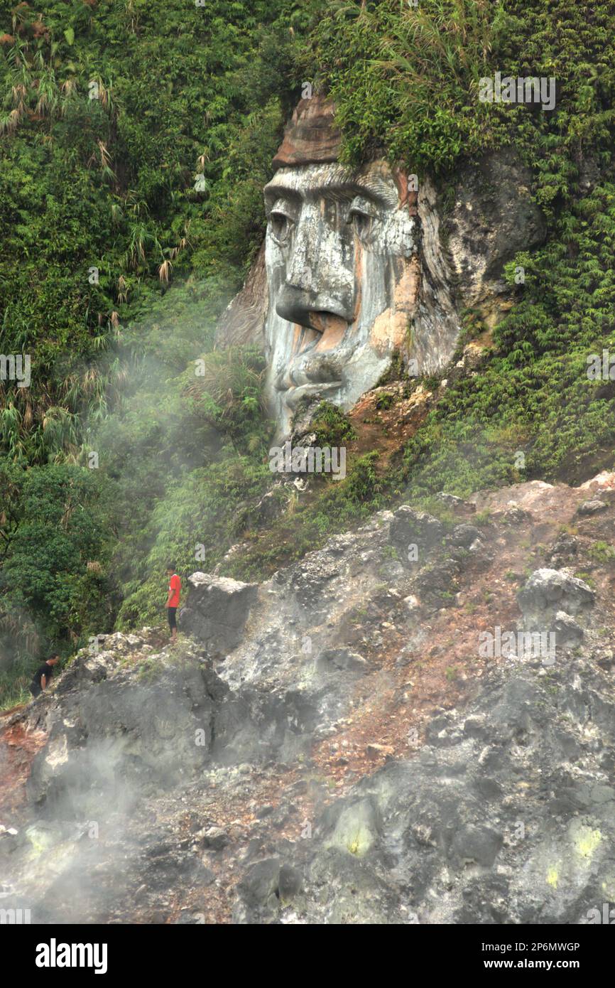 Besucher betreten das Fumarole-Feld, um eine riesige Gesichtsformation zu erreichen, die die Figuren von Toar zeigt, die – zusammen mit Lumimuut – laut lokaler Mythologie als die Vorfahren der Minahasaner gelten. Die Figuren wurden auf einem Hügel in Bukit Kasih erbaut, einem beliebten Ziel für Kultur-, Natur- und religiösen Tourismus im Dorf Kanonang, West Kawangkoan, Minahasa, North Sulawesi, Indonesien. Stockfoto