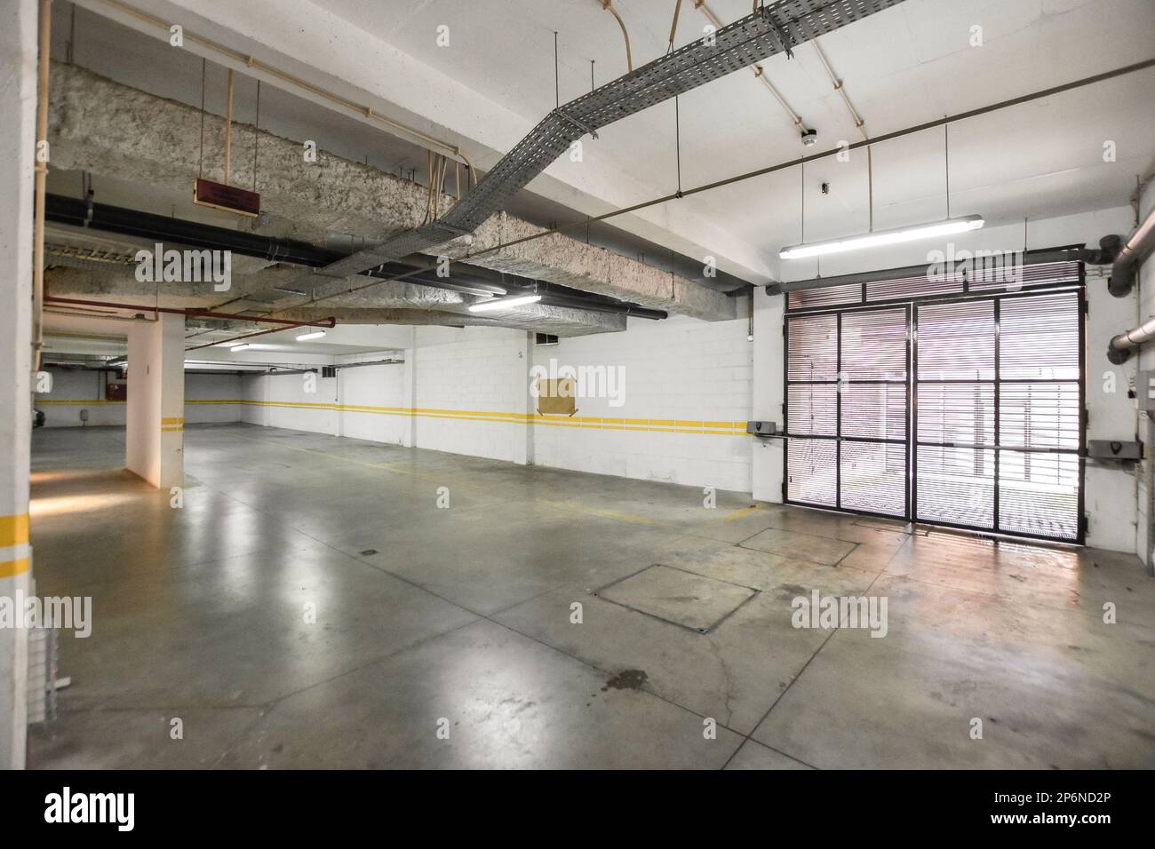 Das Innere eines leeren Parkhauses mit gelben Linien auf dem Boden und weißen Wänden, von außen gesehen Stockfoto
