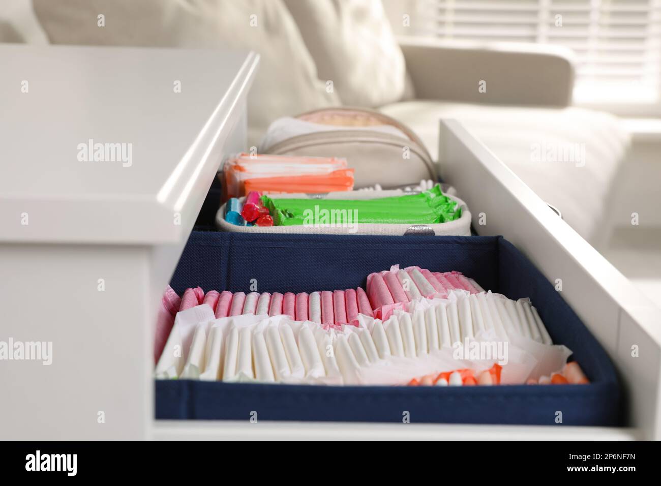 Offene Schublade mit Menstruationseinlagen und Tampons im Innenbereich, Nahaufnahme Stockfoto