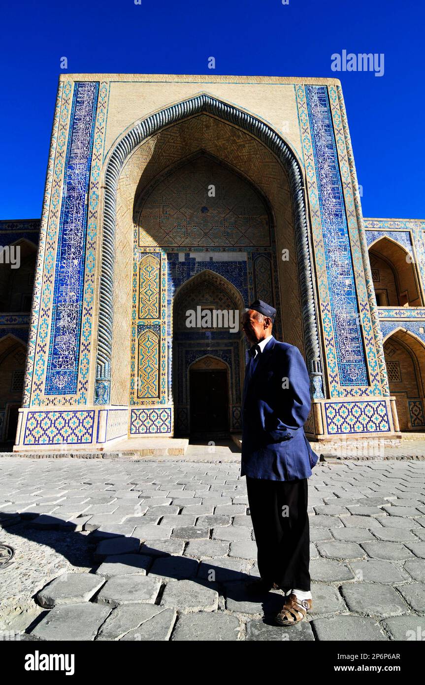 Ein usbekischer Mann steht vor der Ulugbek medressa in Bukhara, Usbekistan. Stockfoto
