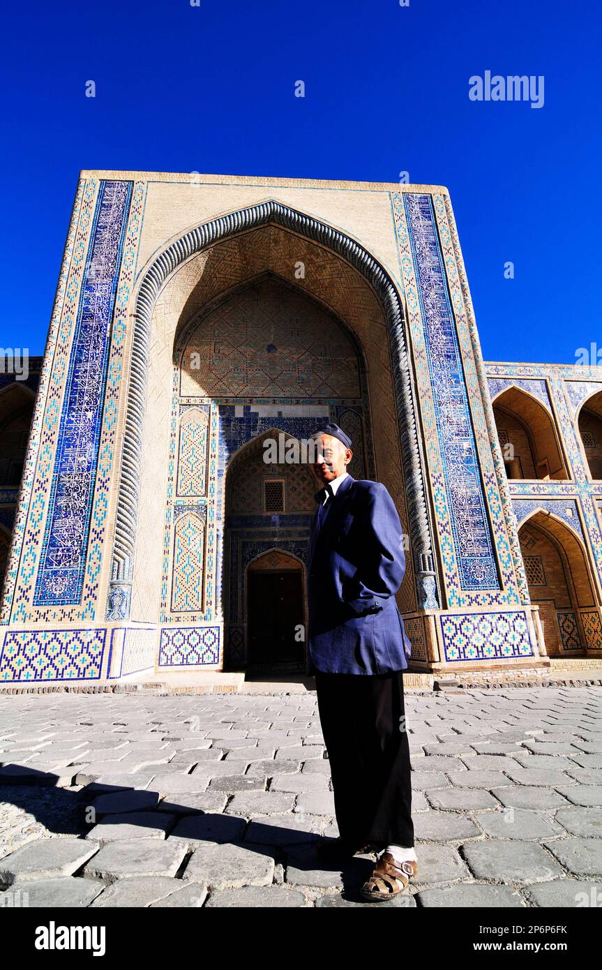 Ein usbekischer Mann steht vor der Ulugbek medressa in Bukhara, Usbekistan. Stockfoto