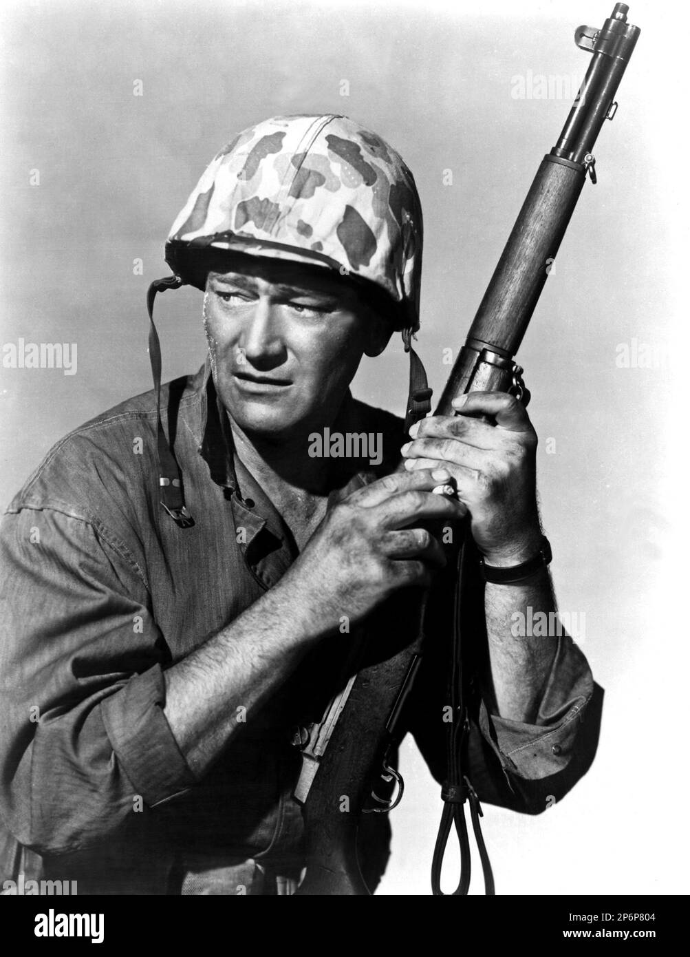 1949 : die gefeierten Filmschauspieler JOHN WAYNE in einem publizistischen Film für DEN Film SANDS OF IWO JIMA ( Iwo Jima , deserto di fuoco ) von Allan Dwan , Aus einem Roman von Brown - CINEMA - ATTORE CINEMATOGRAFICO - Helm - Elmetto - SCHLACHT - BATTAGLIA - Militäruniform - Divisa uniforme militare - FILM - fucile - Waffe - arma - Archivio GBB Stockfoto