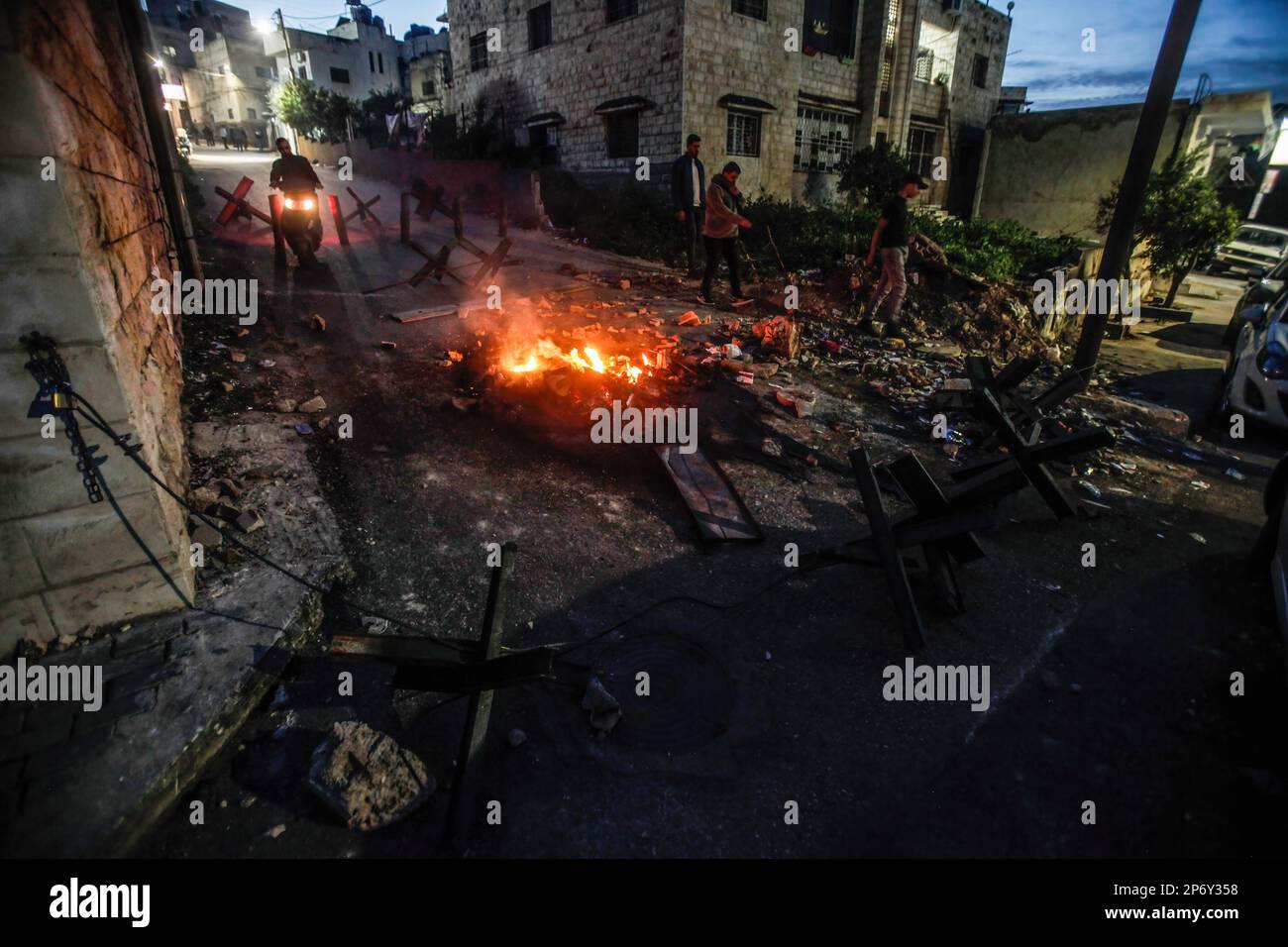 Ein Blick auf ein brennendes Feuer und eiserne Barrieren, die von palästinensischen Jugendlichen mitten auf der Straße aufgestellt wurden, um zu verhindern, dass die israelische Armee das Flüchtlingslager Dschenin in der Nähe der Stadt Dschenin im besetzten Westjordanland stürmt. Große Streitkräfte der israelischen Armee stürmten das Lager Dschenin und zerstörten einen Unterschlupf, in dem sich 6 bewaffnete Palästinenser versteckten, darunter der palästinensische Abdel-Fattah Khrusheh, der am 28. Februar den Schussanschlag auf einen israelischen Siedler in seiner Stadt Hawara verübte. Das palästinensische Gesundheitsministerium sagte, dass 6 Palästinenser bei diesem Angriff getötet wurden. (Foto von Nasser Ishtayeh Stockfoto