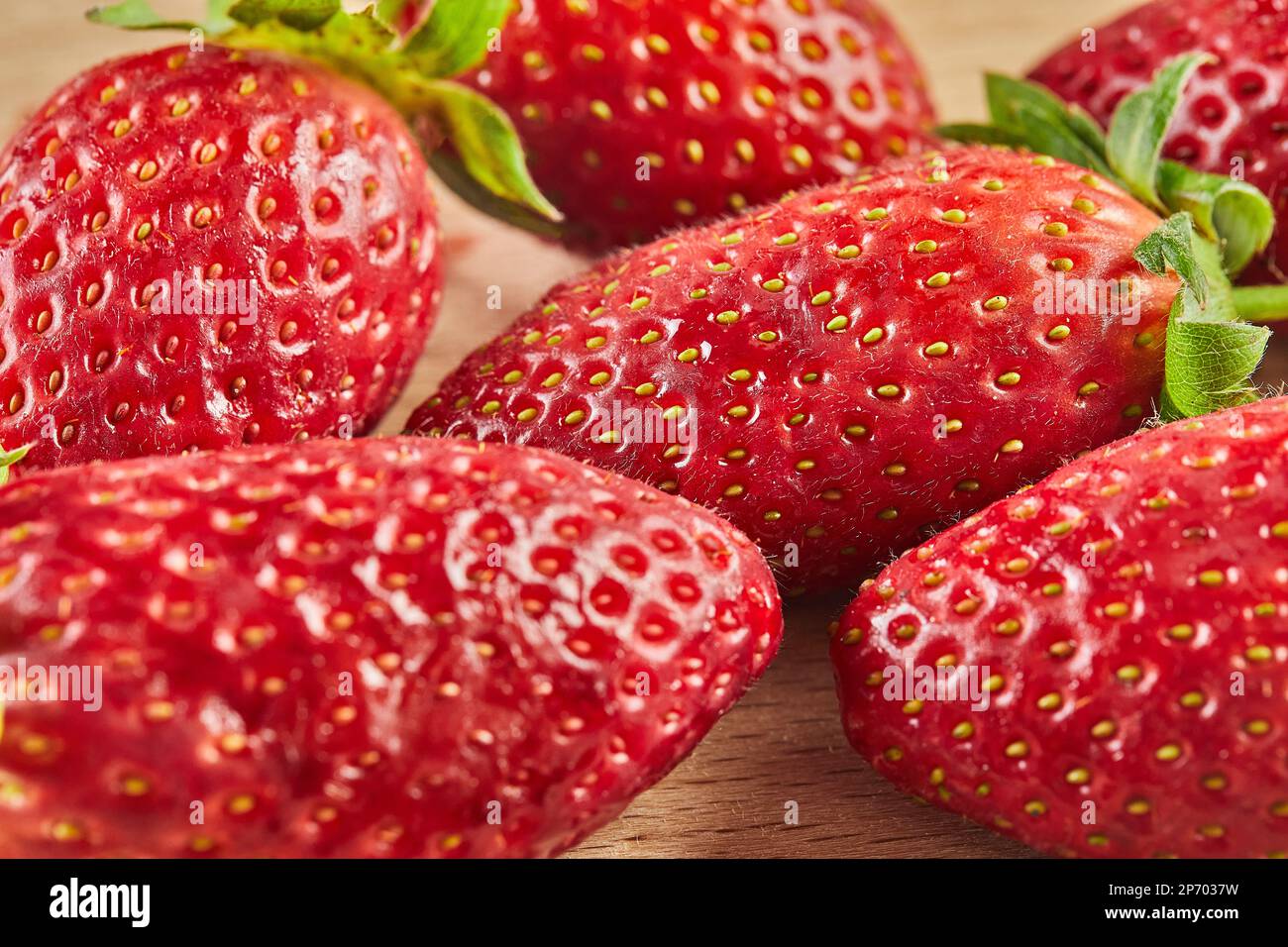 Frisch ausgewählte Erdbeeren, gestapelt auf einer Rutsche auf Holzhintergrund Stockfoto
