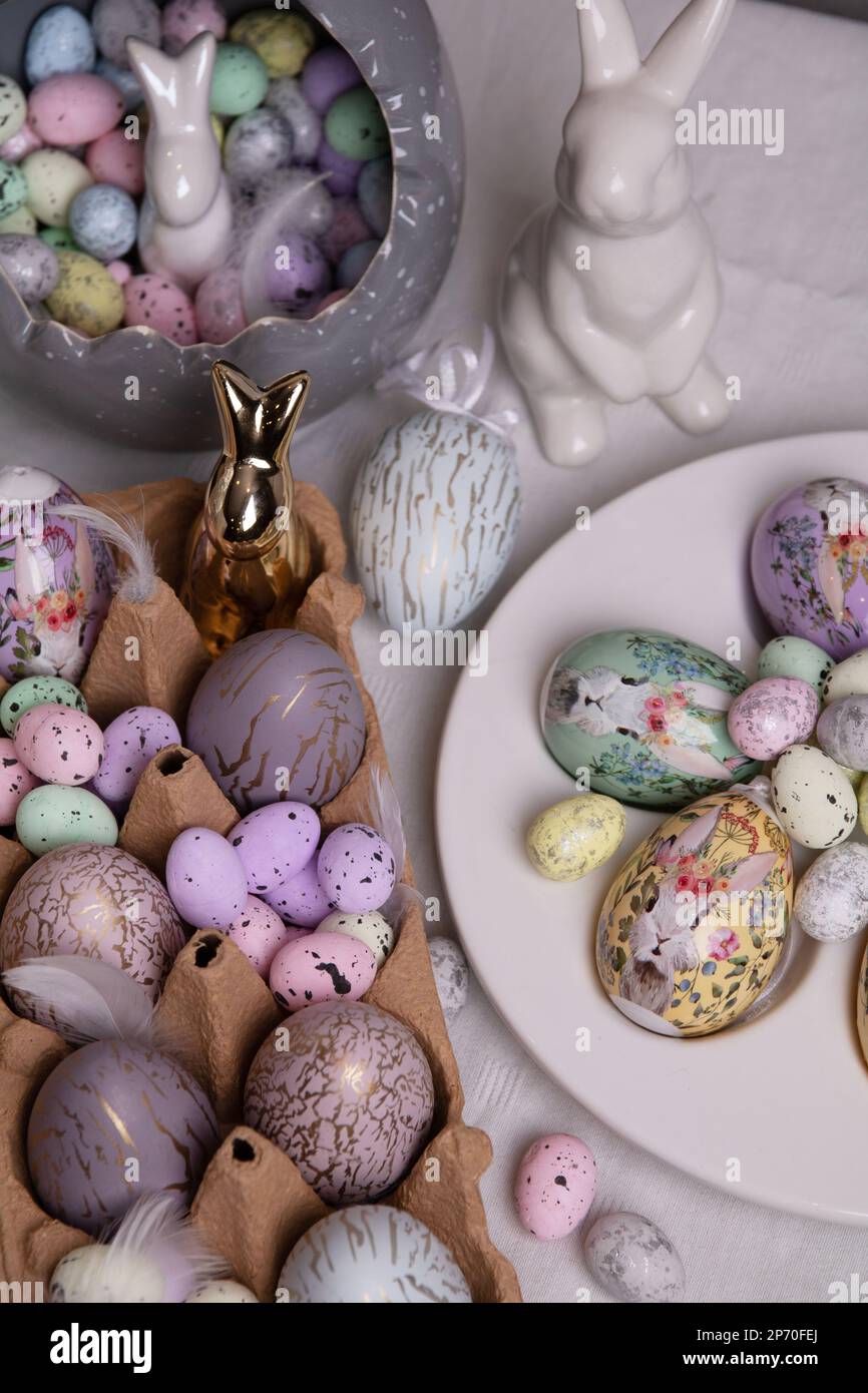 Fotografieren Sie farbenfrohe dekorative Hühnchen- und Wachteleier und ein keramisches Kaninchen auf dem Tisch Stockfoto