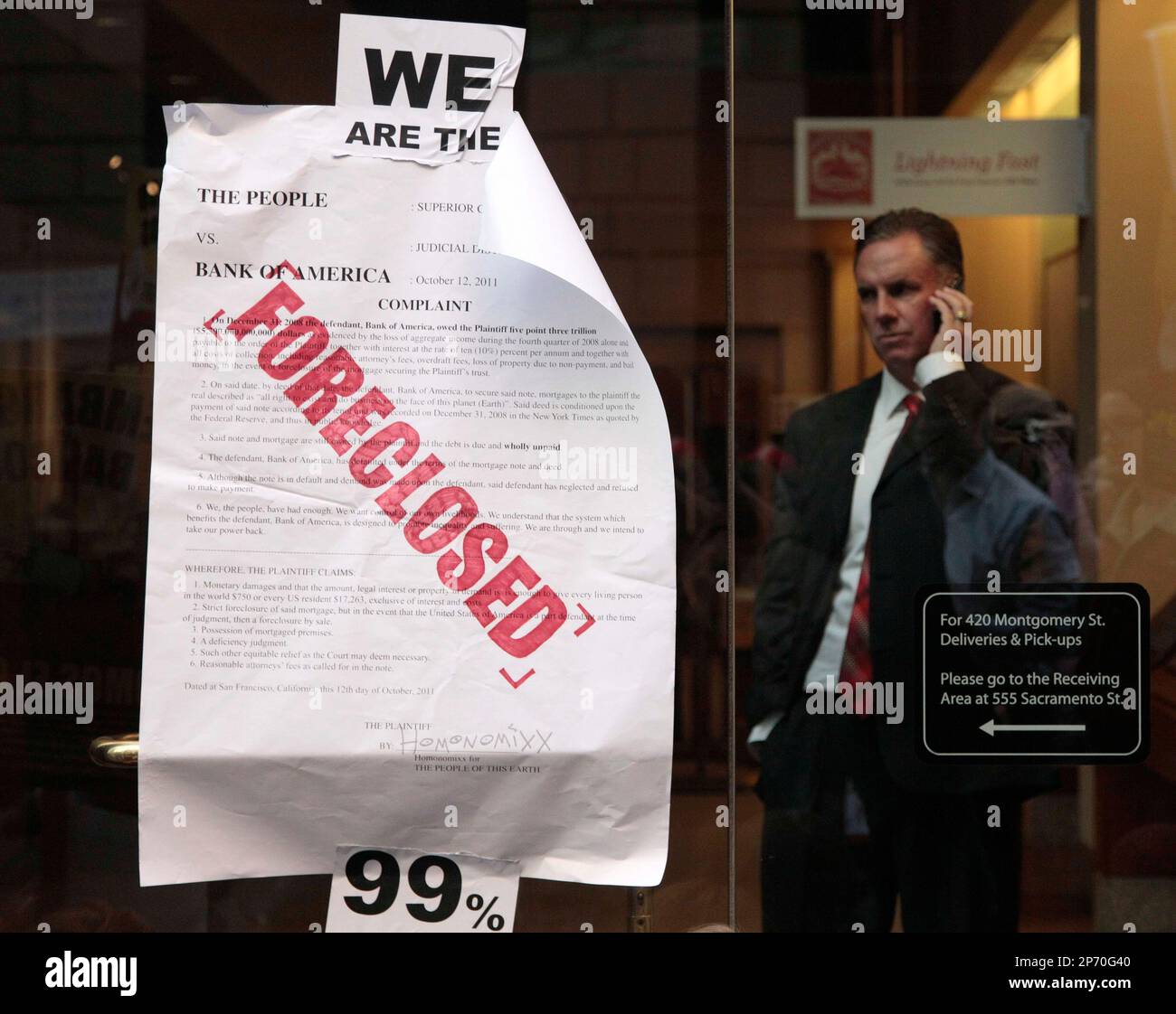 A bank employee stands behind glass as he looks out to protesters blocking an entry way to a Wells Fargo bank in San Francisco, Wednesday, Oct. 12, 2011. Eleven people were arrested Wednesday during an anti-Wall Street rally in front of Wells Fargo Bank headquarters in downtown San Francisco, police said. (AP Photo/Jeff Chiu) Stockfoto