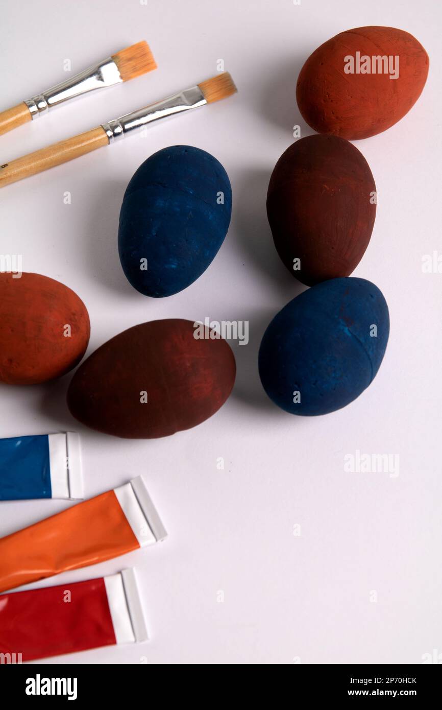 Fotofarbene dekorative Eier auf weißem Hintergrund mit Farben und Pinseln Stockfoto