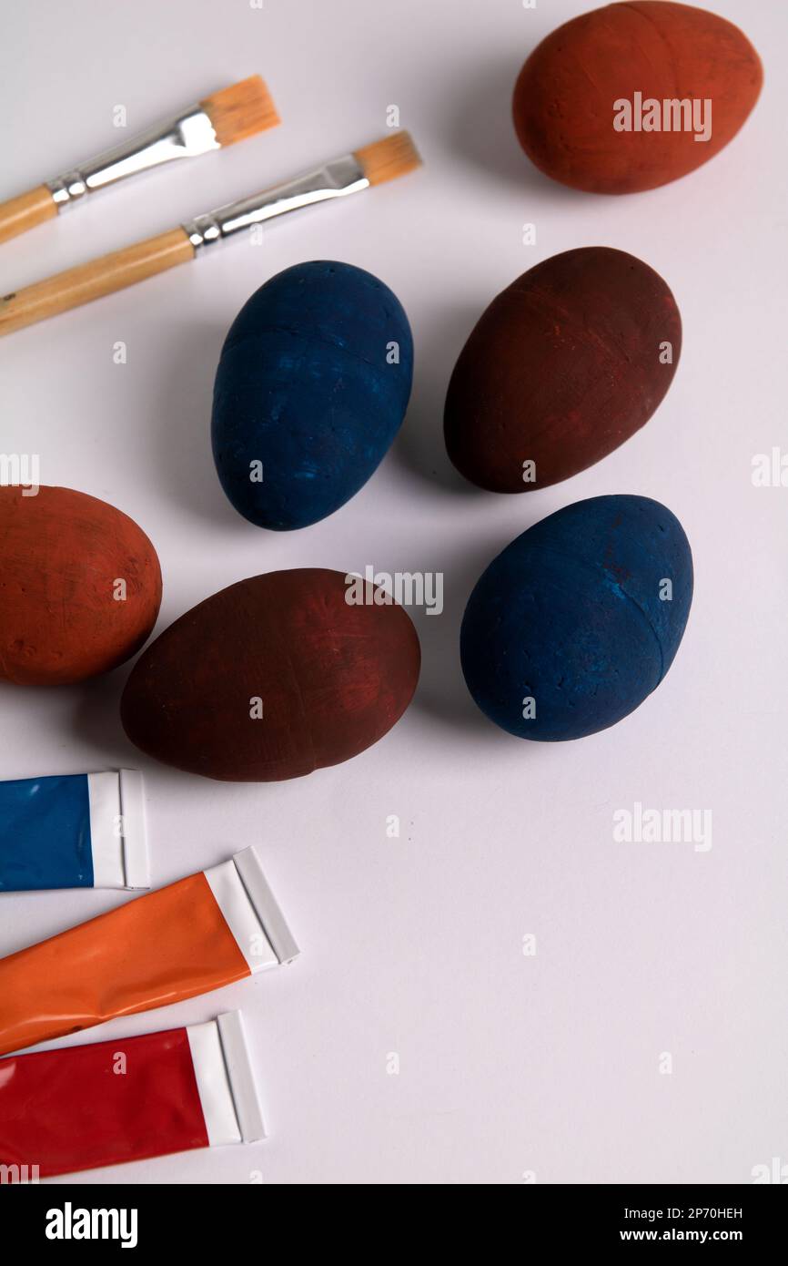 Foto mehrerer bemalter Eier mit Farben in einem Rohr und Pinseln auf weißem Hintergrund Stockfoto