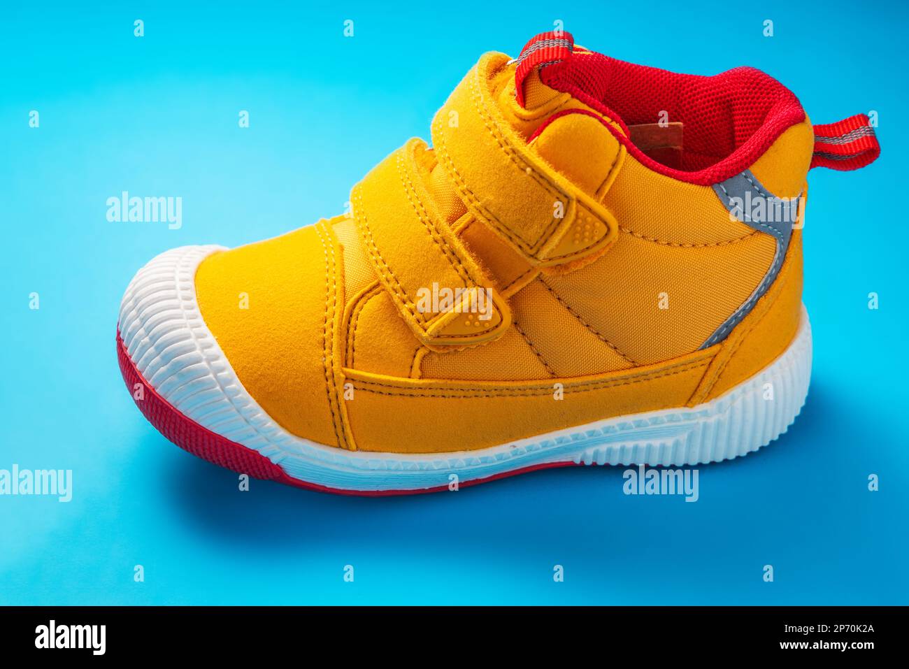 Gelbe Babyschuhe. Kinder Sport Sneaker isoliert auf blauem Hintergrund Stockfoto