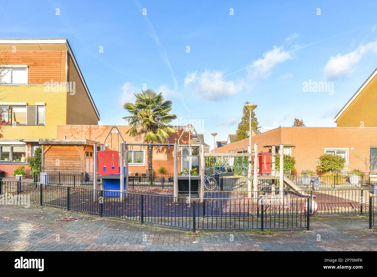 Ein leerer Spielplatz in der Mitte eines Wohngebiets mit Palmen auf beiden Seiten des Spielbereichs und Kinderspielplatz Stockfoto