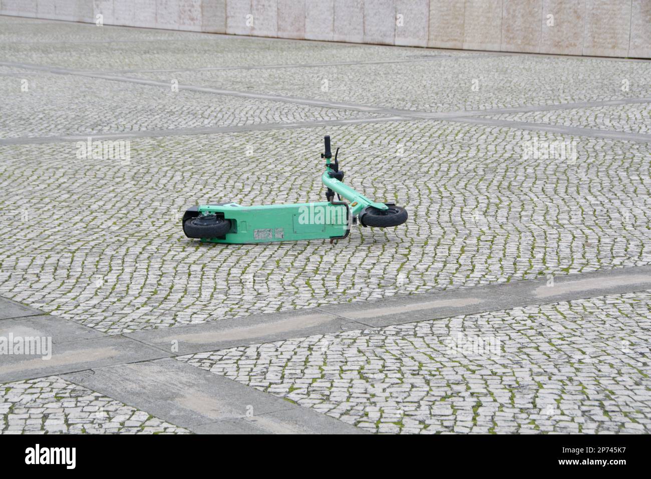 Ein einsamer grüner Elektroroller liegt auf der Straße vor dem Kulturzentrum von Belem. Wird das Rollerunordnung in Touristenstädten zum Problem? Stockfoto