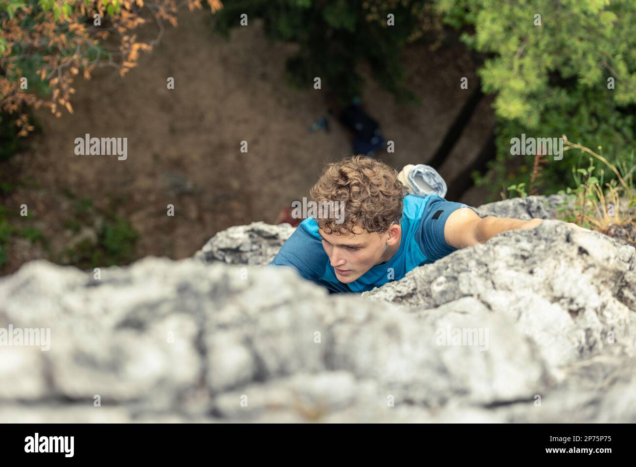 Ein Mann, der auf den Gipfel des Berges klettert. Direkt über der Ansicht. Stockfoto