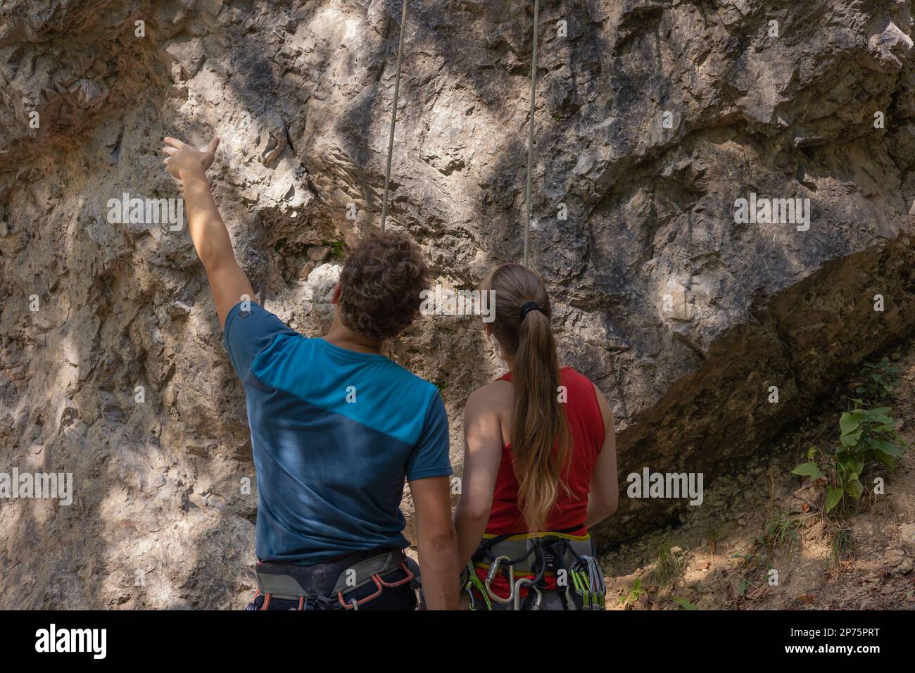Männlicher Kletterlehrer zeigt den richtigen Weg zum erfolgreichen Klettern für weibliche Kletteranfänger Stockfoto