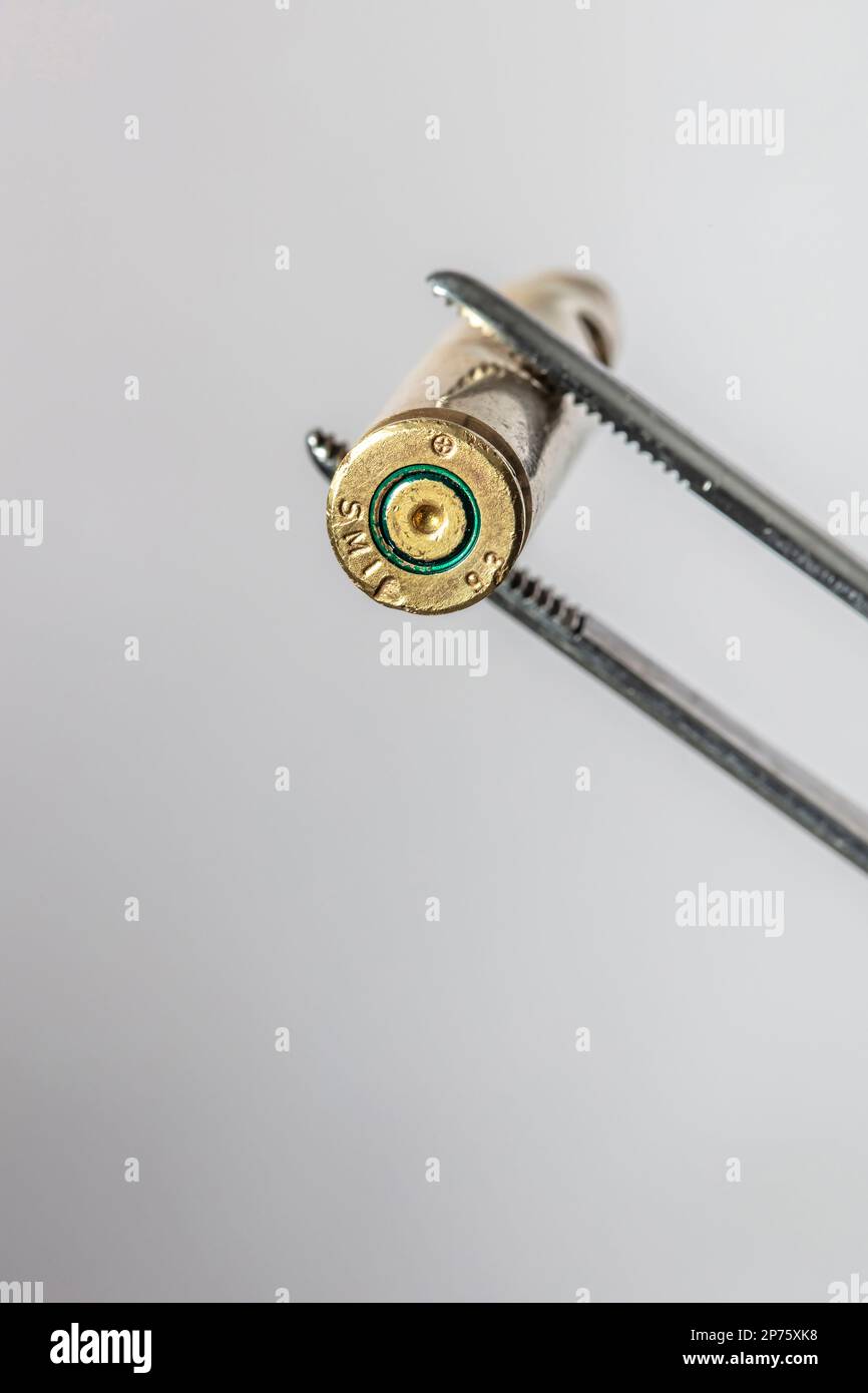 Messinggehäuse wird von einer Stahlpinzette gehalten Stockfoto