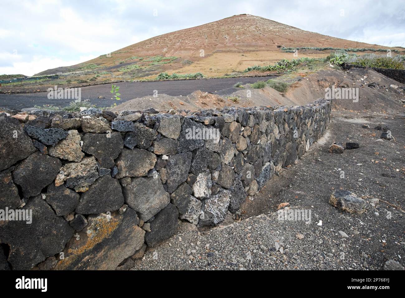 Trockene Steinmauer aus vulkanischem Gestein am Rand eines Feldes in der Nähe eines Vulkans auf Lanzarote, Kanarische Inseln, Spanien Stockfoto