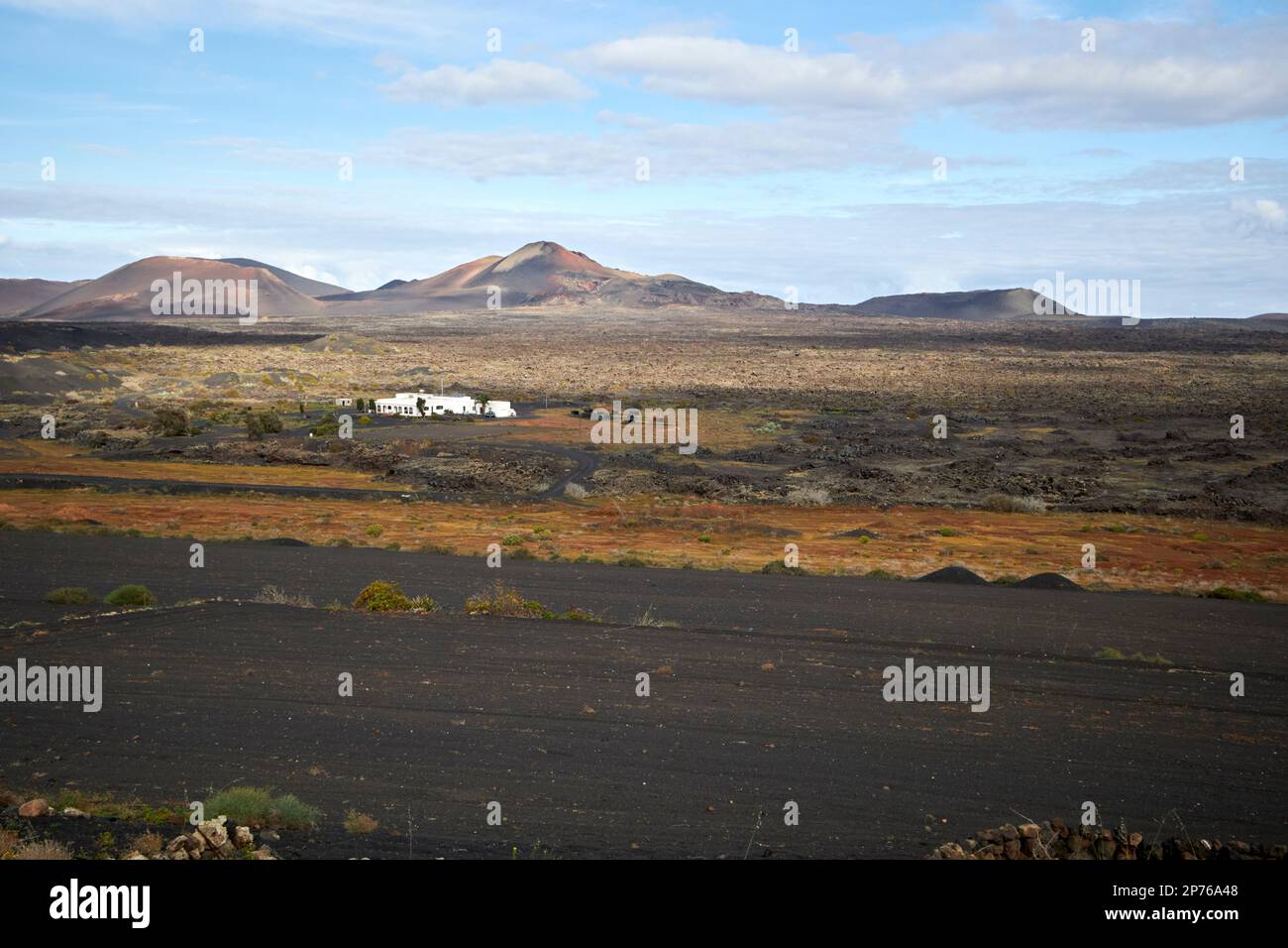 picon bedeckte Felder und Bauernhof in abgelegener Weinregion La geria mit Vulkanen im Hintergrund Lanzarote, Kanarische Inseln, Spanien Stockfoto