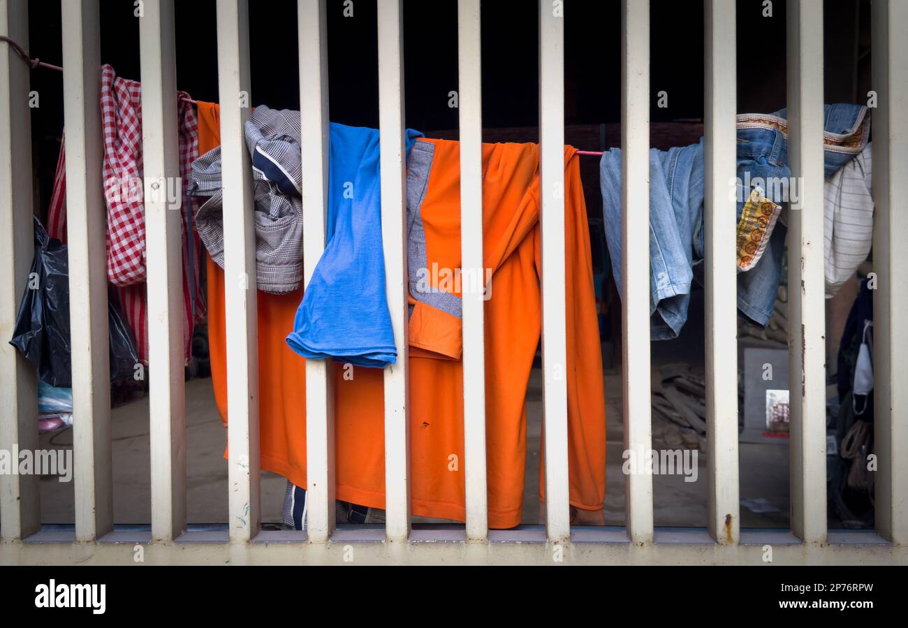 Kleidung an einer Leine, die sich hinter einem Sicherheitsgitter aus Stahl in Phnom Penh, Kambodscha, erstreckt. Stockfoto