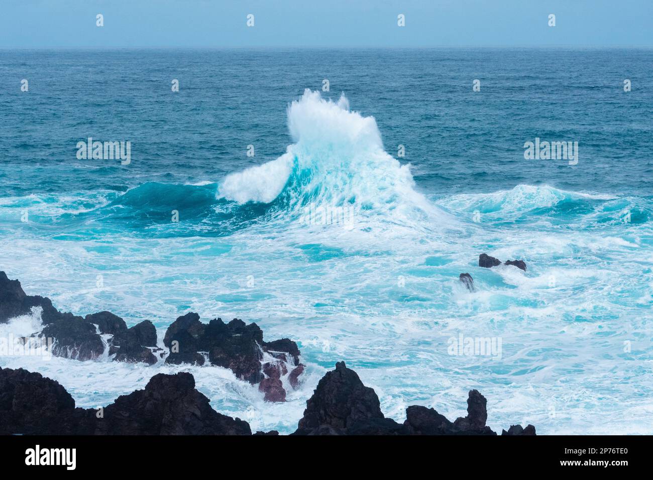 Wellen schlagen auf Felsen und machen einen großen Spritzer Stockfoto