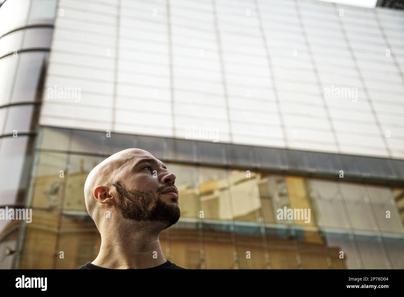 Ehrgeiziger, seriöser junger Geschäftsmann, der in das Zukunftskonzept blickt. Bärtiger kaukasischer Mann gegen ein Gebäude mit Kopierraum Stockfoto