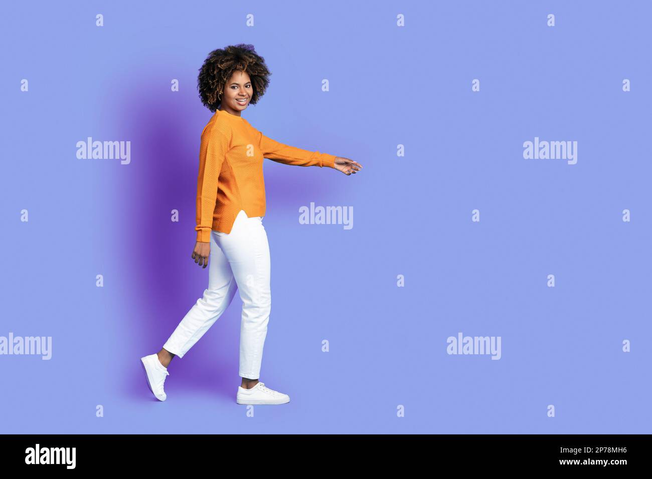Fröhliche, elegante, geschwungene schwarze Frau, die in Richtung Kopierbereich geht Stockfoto